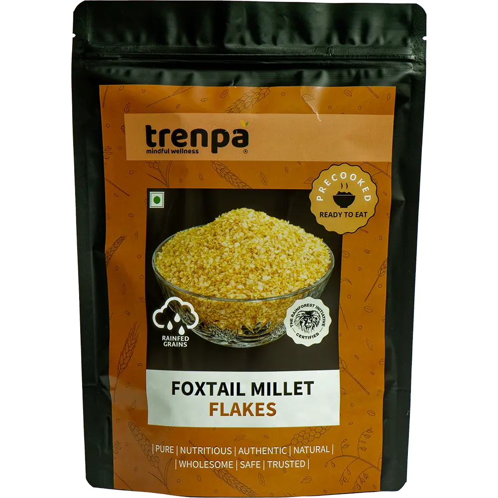 A packet of Trenpa Foxtail Millet Flakes features an image of the grains in a glass bowl on its brown packaging, which displays branding and details, emphasizing that these ready-to-eat flakes support heart health.